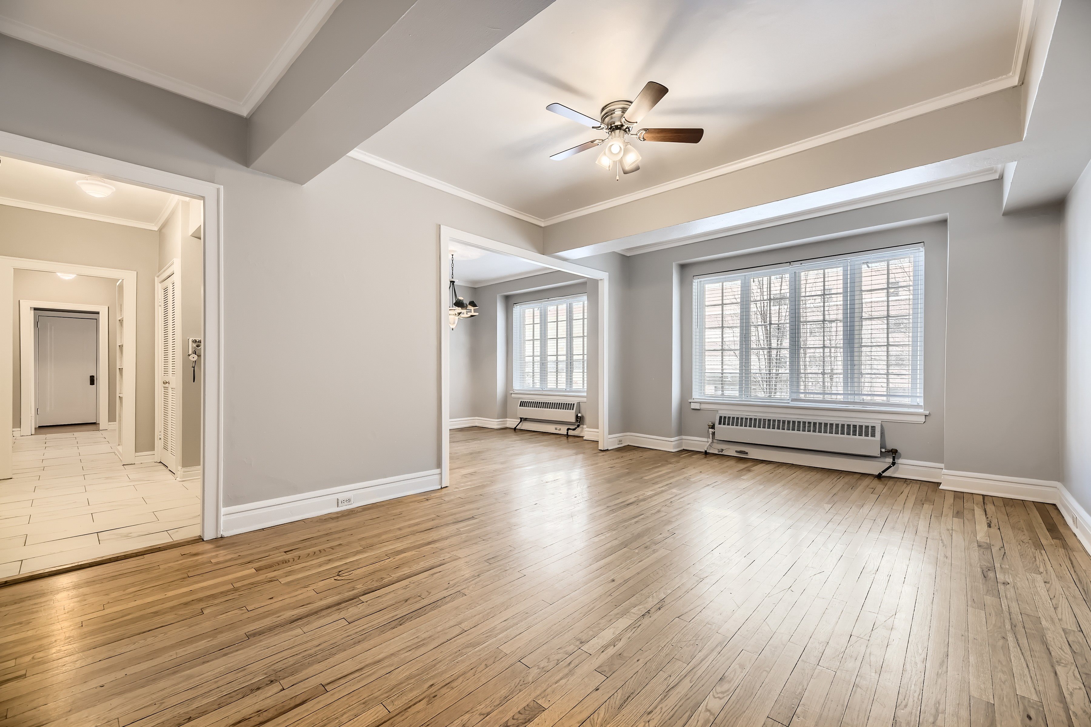 A spacious room with wooden floors and a ceiling fan.
